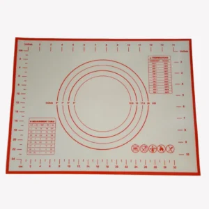 Vit bakmatta i silikon med rött tryck. Mattan har både centimeter- och tumskalor längs kanterna. I mitten finns koncentriska cirklar med storlekar från 12,5 cm till 25 cm. På mattan finns även en temperaturkonverteringstabell och en omvandlingstabell för mått. Längst ner syns symboler som visar att mattan är tillverkad av livsmedelsklassad silikon, tål diskmaskin, tål ugn, inte bör skäras på och är non-stick.